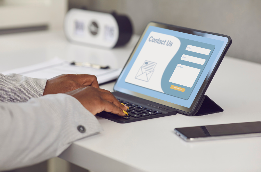 Woman on a tablet typing on a keyboard filling out a contact form online.